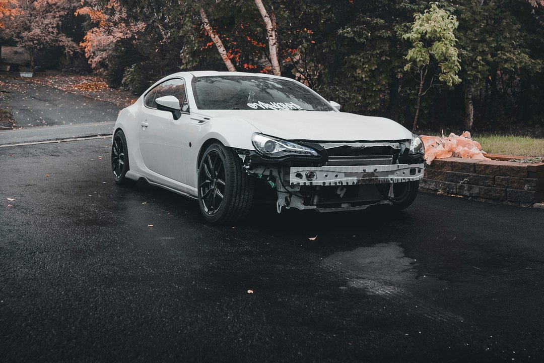 White vehicle without its front bumper; the photograph alone does not explain its history