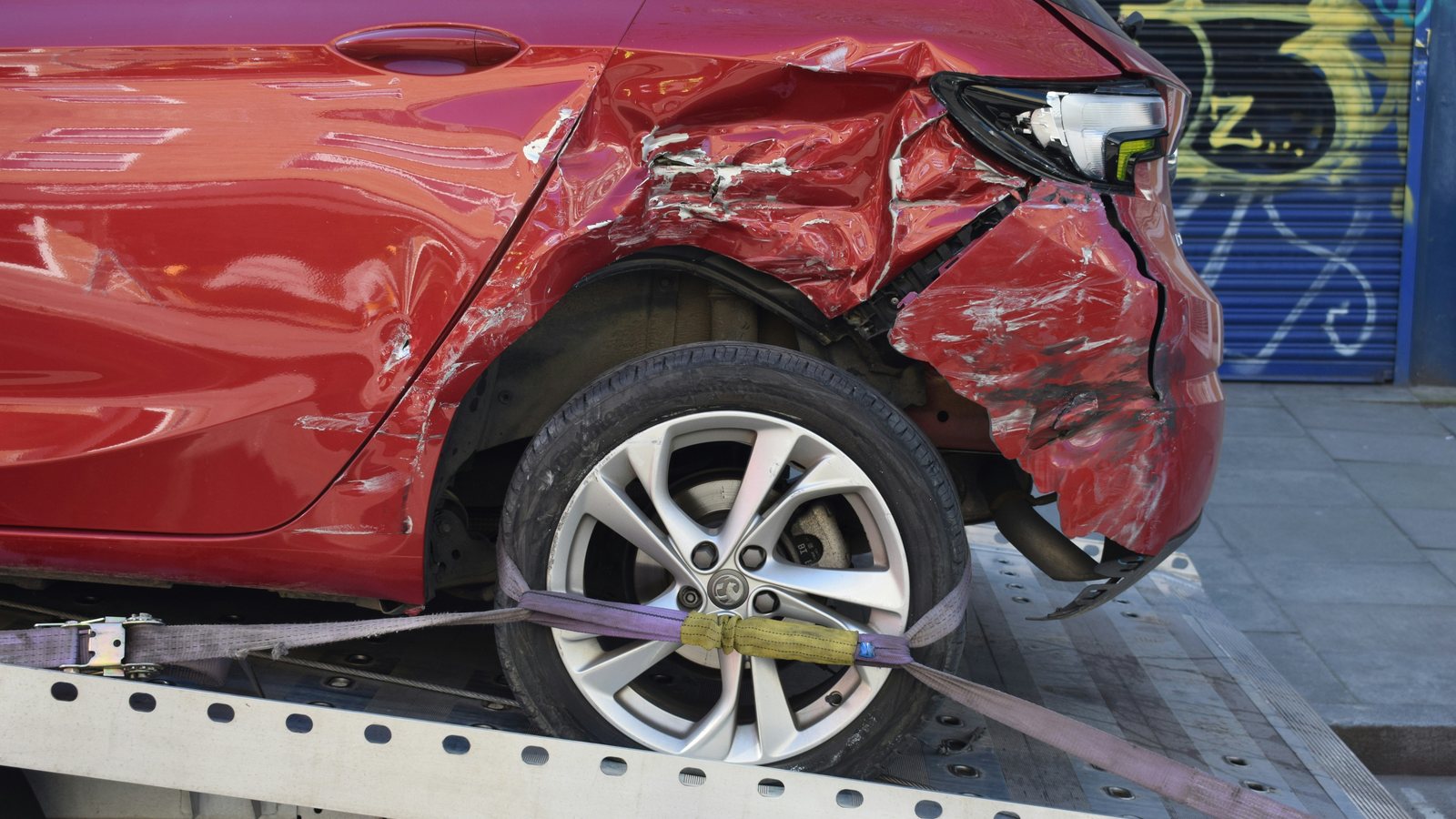 Accident damage to a red vehicle on a recovery truck; illustrative photograph